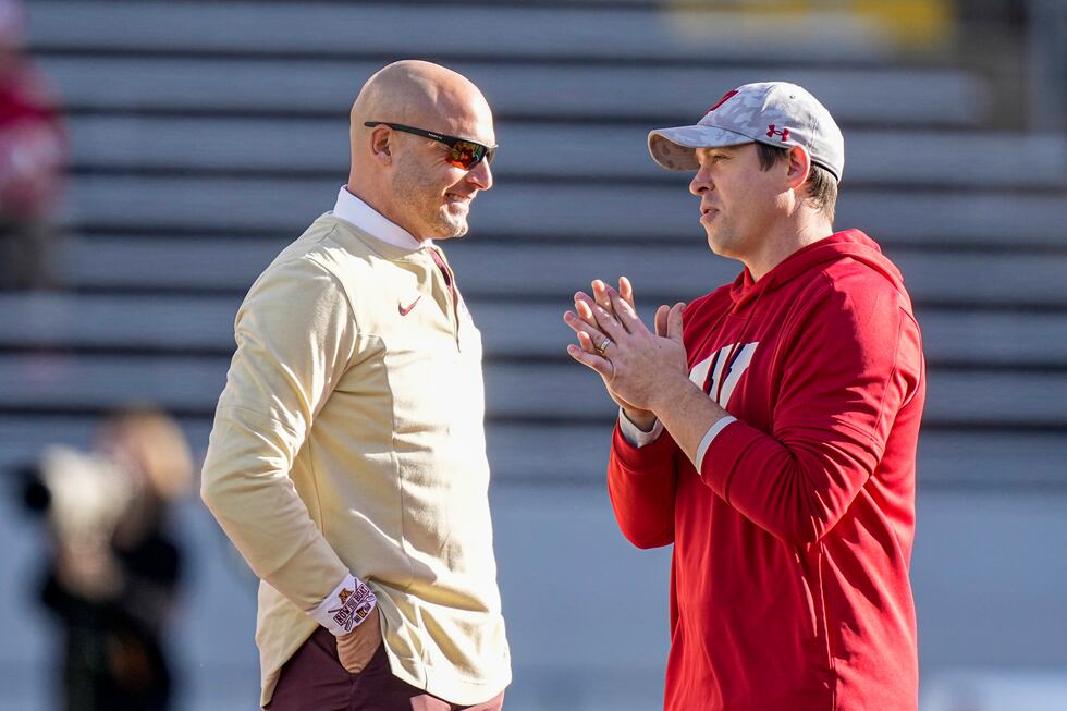 Wisconsin interim head coach Jim Leonhard, right and Minnesota head coach P.J. Fleck talk on...